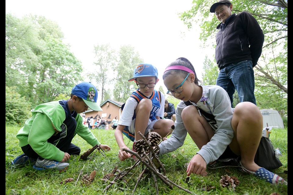 Aaron, 7, Gregory, 12, and Elisa, 10, build a gnome home at the Forest Fairy Gathering to mark the seasonal opening of the Burnaby Lake Nature House.