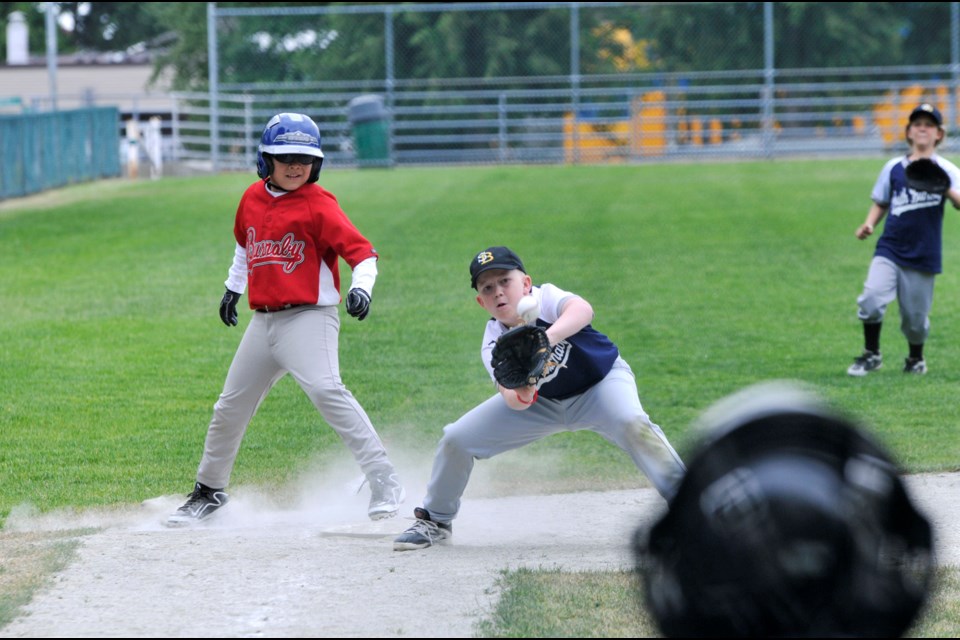 Chung Chow photo U-11 Mosquito baseball at Bonsor Park Redbulls (red) vs Dodgers Dodger 3rd baseman Caleb Knutson trying to catch out Redbulls Elvin Zukic