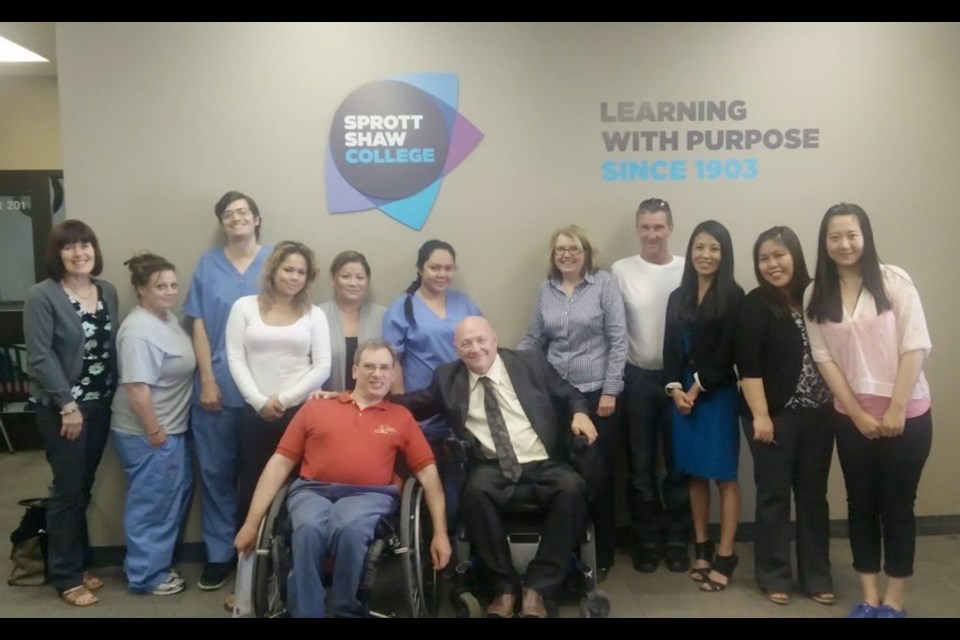 Shaun Kennett, front left, and Sprott Shaw College career adviser Phil Nealy, front right, with Sprott Shaw students who helped raise money to buy Kennett a $3,200 hand cycle.