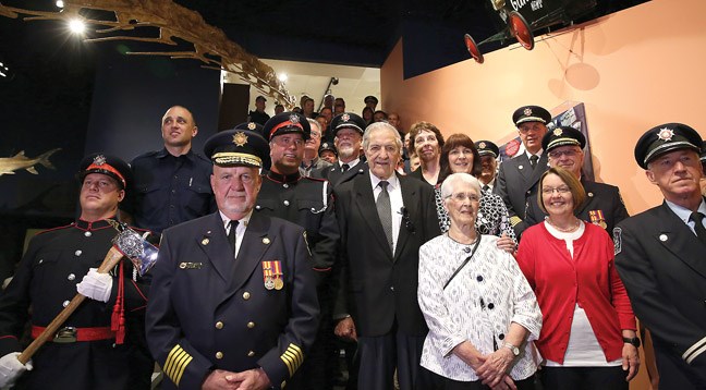 Members of the Prince George Fire Department, alumni of the Prince George Fire Department and other dignitaries gather on the stairs leading up to new 100 years of Fire exhibit at Exploration Place.