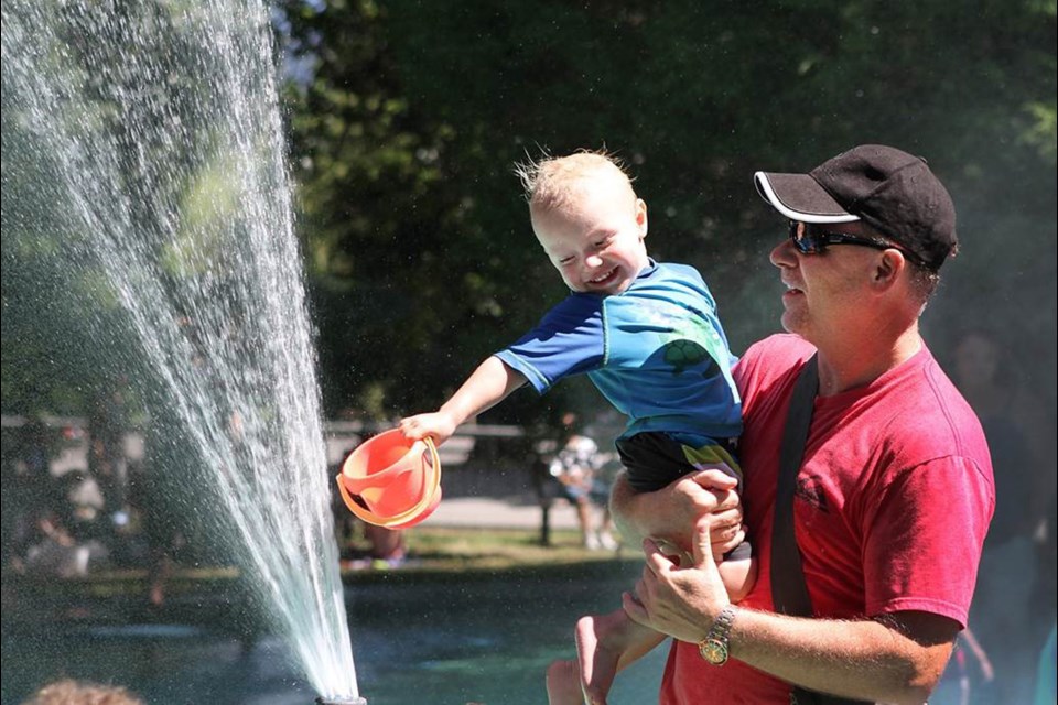 Bo, 2, tries to get water for his bucket with help from grandpa Brad Girard at the water park at Queen's Park.