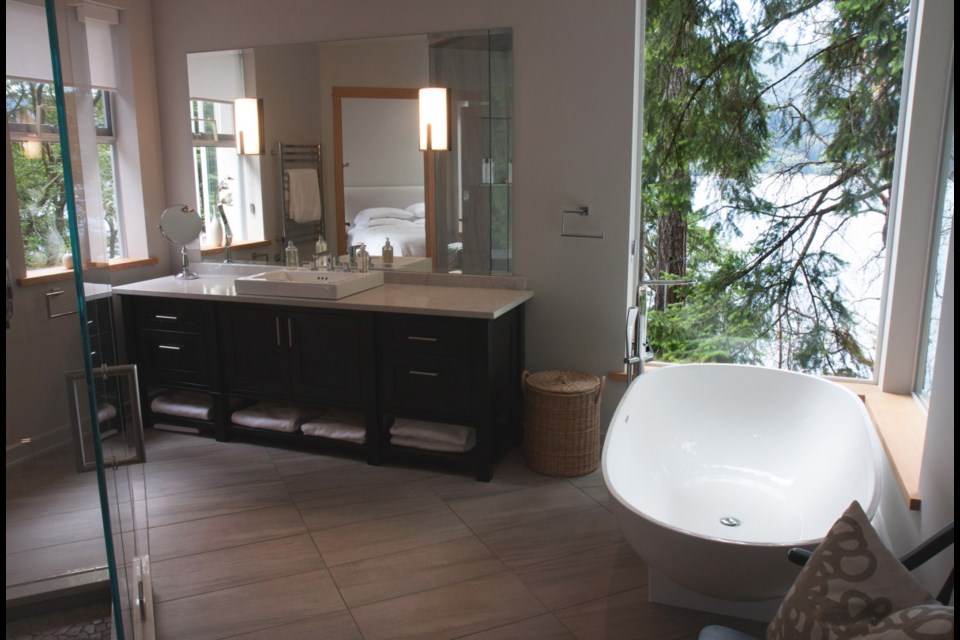 The master bath has a giant walk-in glass shower with near-invisible seams thanks to mitred corners. A large mirror over custom cabinets expands the area.