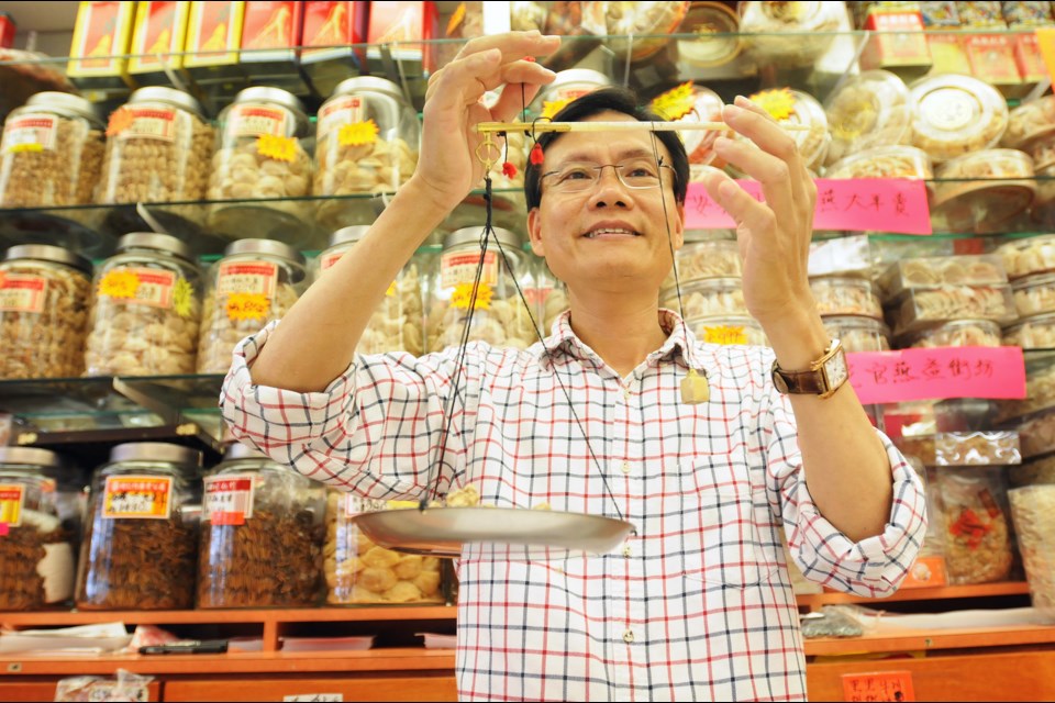 Salesperson Michael Chung weighs medicinal products at Cheung Sing Herbal and Birds Nest Co. in Chinatown. He believes the community’s still-thriving traditional herbal shops will remain for at least a decade, even as the customer base expands to neighbourhoods throughout Metro Vancouver. Photo Dan Toulgoet