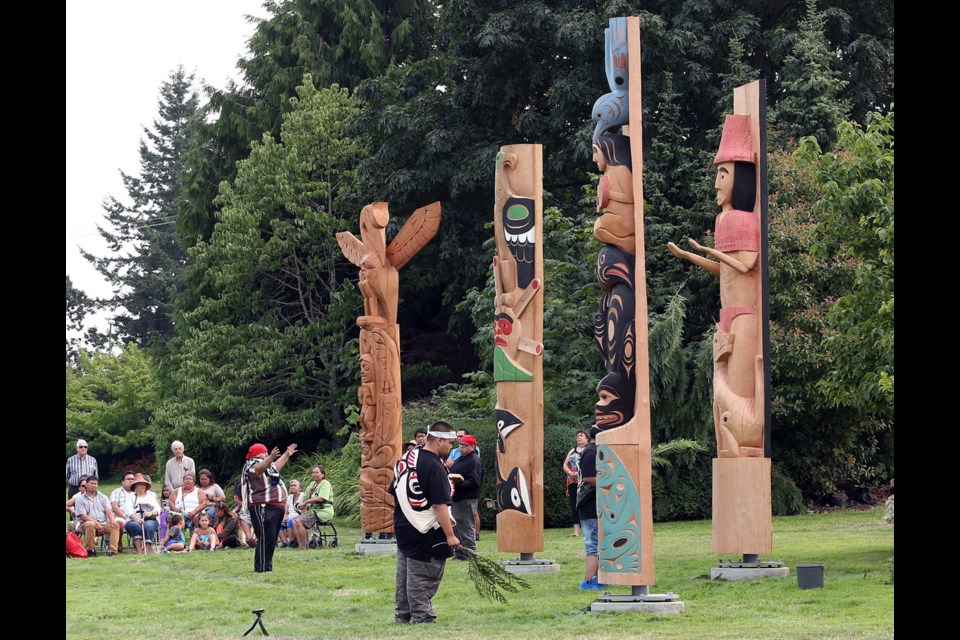 Elder Fred Charlie, left, from Tseycum, blesses the new totem poles at Saanich Peninsula Hospital on Monday. The welcome poles marking First Nations territory will be unveiled publicly at 3 p.m. today.