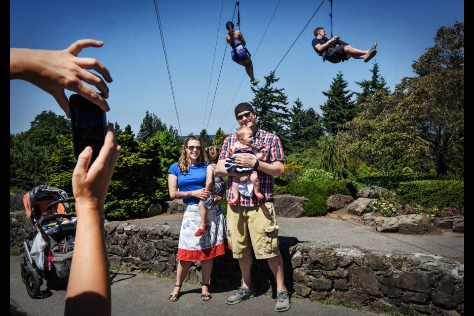 First-time visitors to Queen Elizabeth Park Karen and Nate Whistler with daughters Hazel and Fiona, wanted a family photograph taken in front of the park’s temporary zipline Saturday morning. Photograph by: Rebecca Blissett