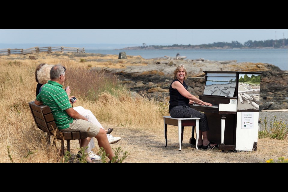 Wednesday: Kim Kerr of Oakville, Ont., plays a painted piano at Cattle Point to the delight of relatives Carol Kerr of Milton, Ont., centre, and Sharon and George Garrett of Nanoose Bay.