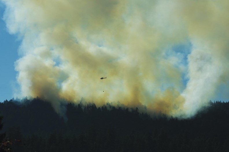 Fire Fight: A helicopter buckets water over the Sechelt fire on July 3, as seen from Gale Avenue North. See more fire photos in our online galleries.