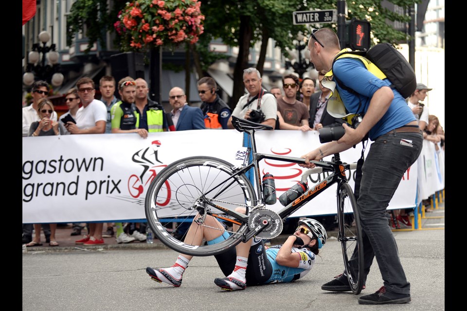 A race marshal helps a cyclist who took a spill during the Global Relay Gastown Grand Prix July 15, 2015. Photo Jennifer Gauthier