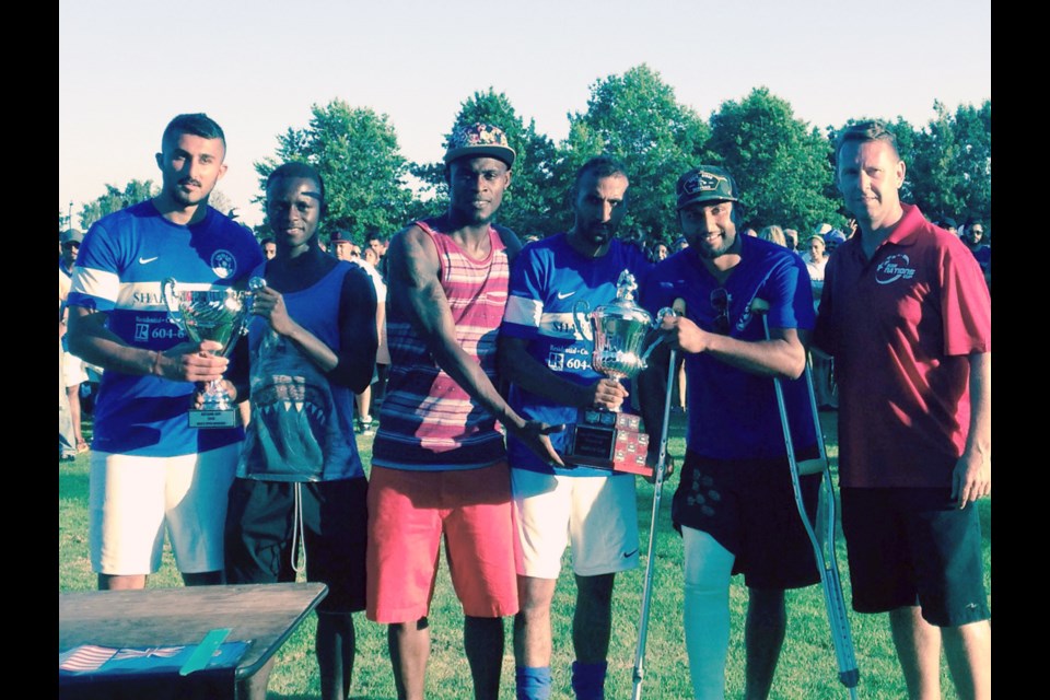 Vancouver Whitecaps FC players Kekuta Manneh (left) and Gershon Koffie, along with Nations Cup president Jeff Wilson (far right) present the Open Division championship trophies to India following a 2-1 overtime win over Germany at the 36th annual summer soccer tournament on Sunday night.