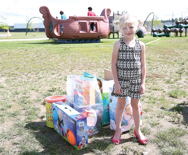 Lexi Shymanski, 5, stands in front of some of the toys that were donated at Peter's Toy Drive which took place at the Duchess Park Playground on Sunday.