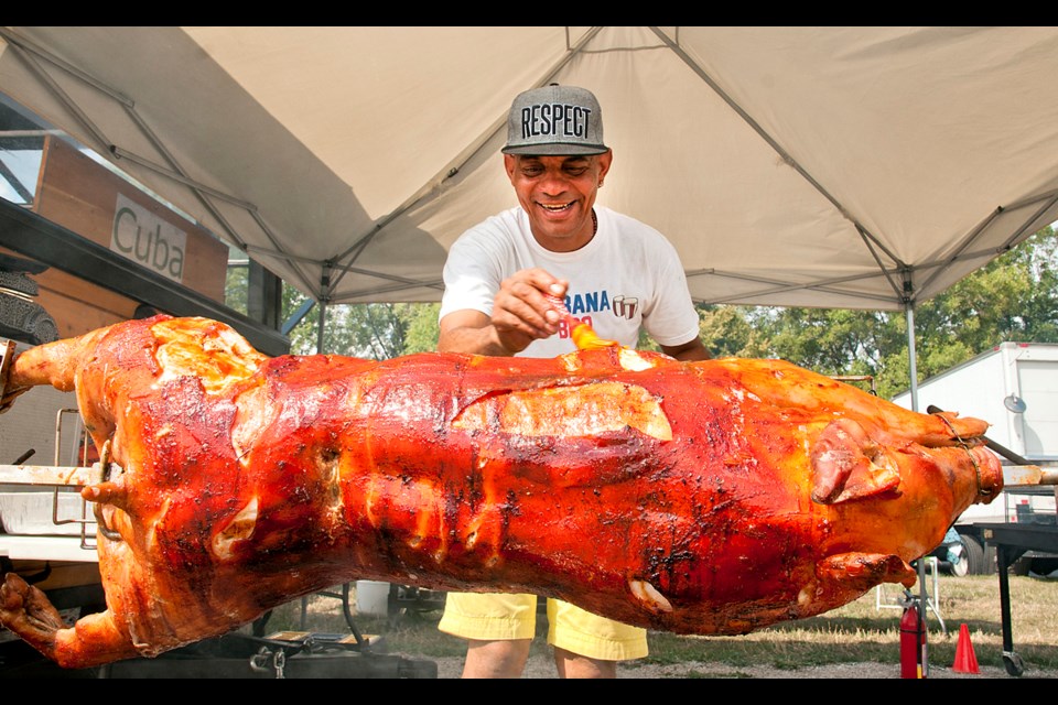 Carlos Piz bastes a whole pig on an open spit for a Cuban barbecue. Photo Chung Chow