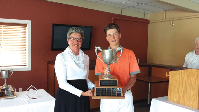 Golf club president Rita Grenville presents a trophy to Myles Killackey, Men's Club Champion.