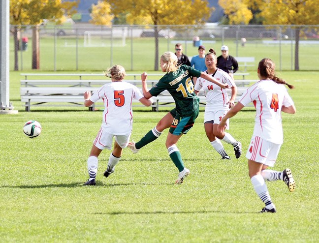 Maddy Doucett manages to get the shot off before the defender reaches her during Canada West women's soccer action on Sunday at the North Cariboo Senior Soccer League fields. The UNBC Timberwolves (green) women's soccer team was at home as they took on the TRU Wolfpack (white).