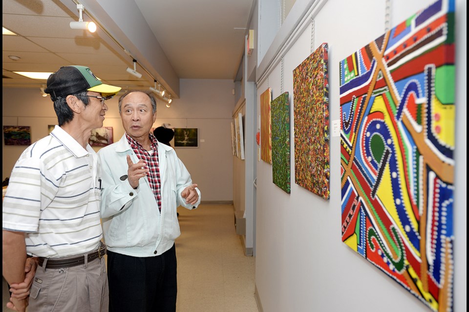 Gallery-goers take in Carol Rose's acrylics at the Potpourri opening.