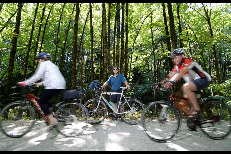 Dennis Hansen, chair of HUB Burnaby, on his favorite bike path, the Central Valley Greenway stretch along the Brunette River, as other HUB members pedal past.