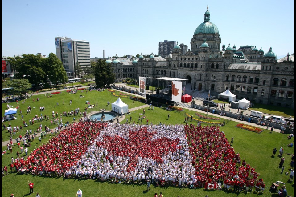 Hundreds of people gather on the legislature lawn, dressed in red and white, to form the Canada Day living flag. July 1, 2013.