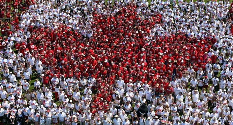 People dressed in red and white form a living Canadian flag on the lawn of the legislature. July 1,