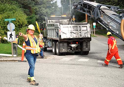 Keeping a smile on your face helps, whether you’re a flagger, such as Greenscapes’ Jewal Maxwell, a person trying to drive through Snug Cove, or a member of the paving crew that is giving the main thoroughfare a new asphalt surface this week.