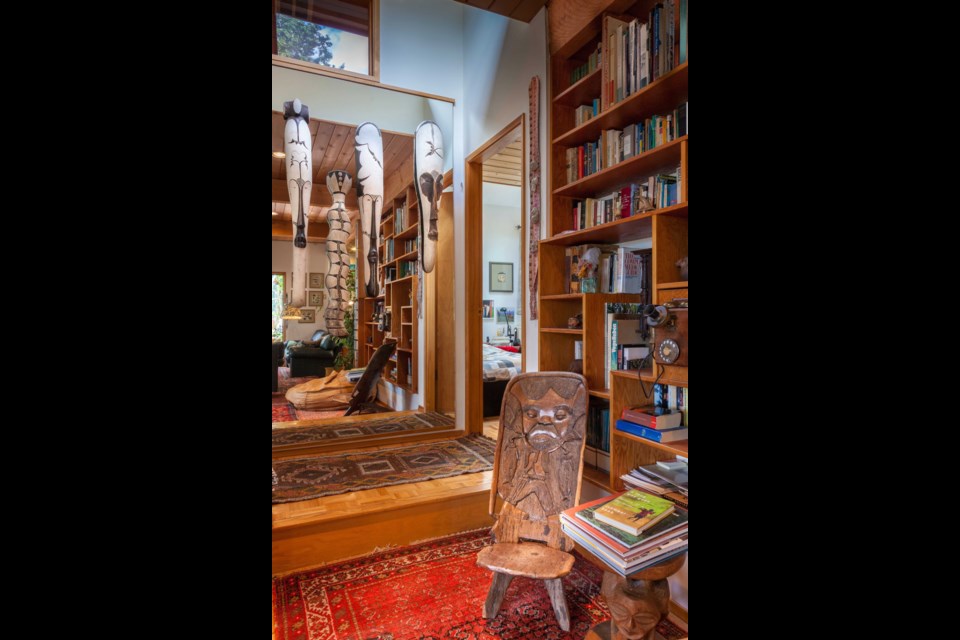 Reflected in the front hall mirror are masks from Cameroon and a carved chief&rsquo;s chair from Zambia.