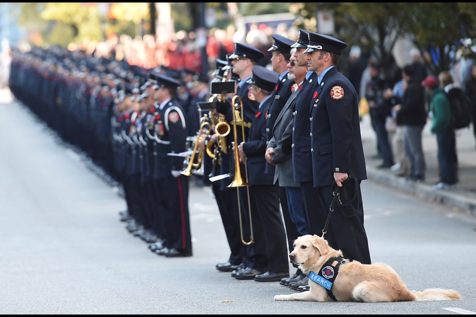 Firefighter Jeff Snider stood with Huddleston, Flynn Lamont’s service dog, during the ceremony.