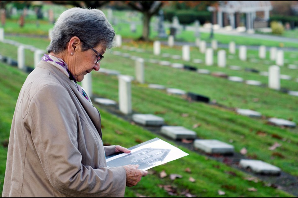 New West resident Marie-Hélène Fekete-Piskorik visits war graves at the Fraser Cemetery with a photo of her childhood home in Belgium.