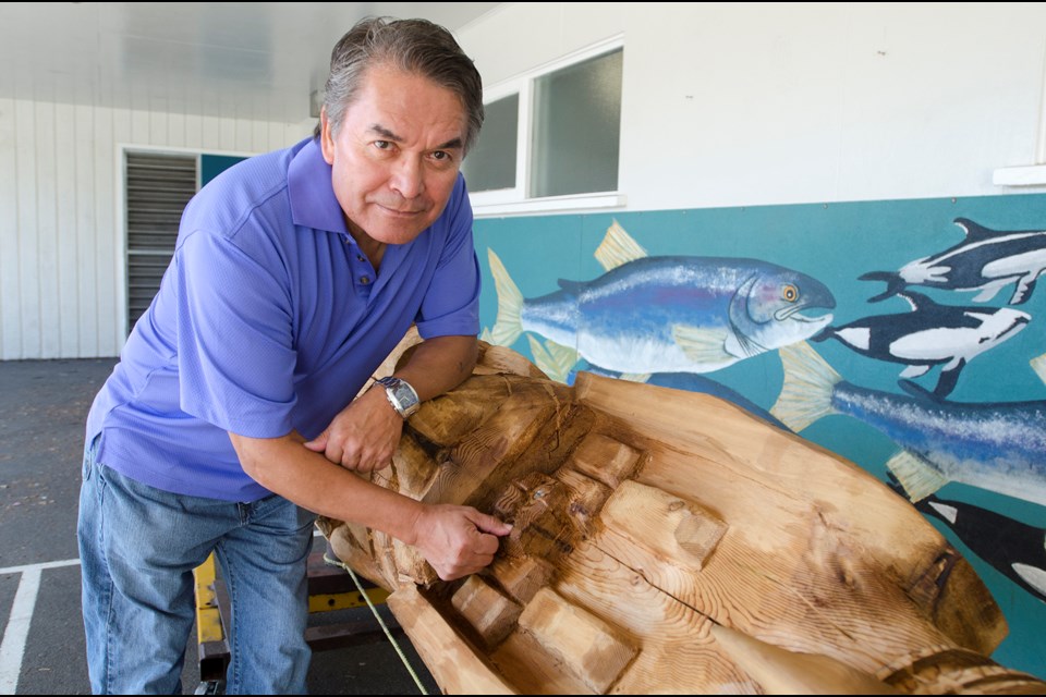 First Nations carver Jackie Timothy places an abalone-shell eye onto a human figure in a totem pole he recently completed for Brentwood Park Elementary. The pole was dedicated at a ceremony at the school last month.