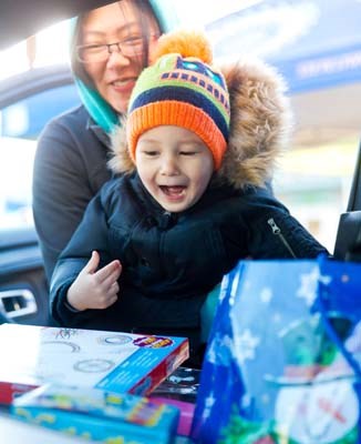 Oliver Edge, with assistance from mom Stephanie, tosses a toy into the police cruiser at Ironwood shopping mall on Saturday as part of Richmond RCMP’s ‘Stuff the Cruiser’ event. The toys collected went to the Richmond Christmas Fund, which helps out low-income families.