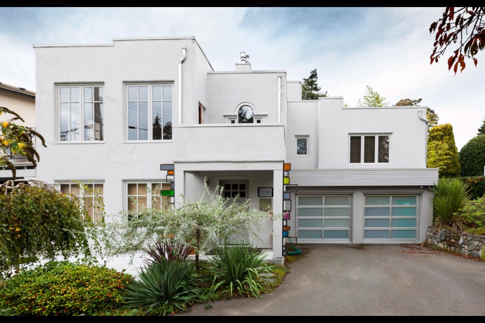The home features a grouping of rectangular elements and is stark white, inside and out. The former carport was closed in with glass garage doors to create an art studio.