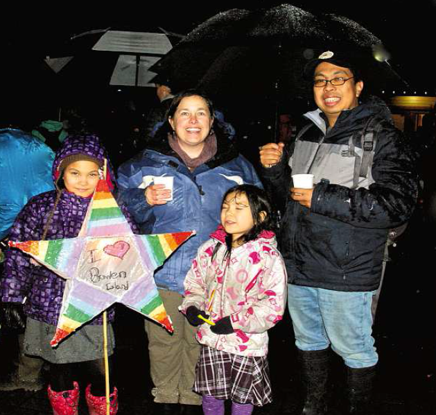 Soaking wet but still having fun, Hannah holds a home-made lantern beside sister Abbie, and with mom Micaele and dad Michael Florendo.