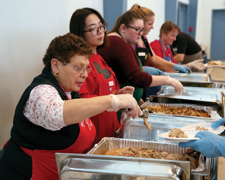Volunteers Marie Carter, left, and Amanda Li, right, dish out turkey on Christmas Day at Sacred Heart Church. The St. Vincent de Paul Society put on their annual Christmas lunch, which featured turkey with all the trimmings, and everyone was welcome to come enjoy. Citizen Photo by James Doyle December 25, 2015