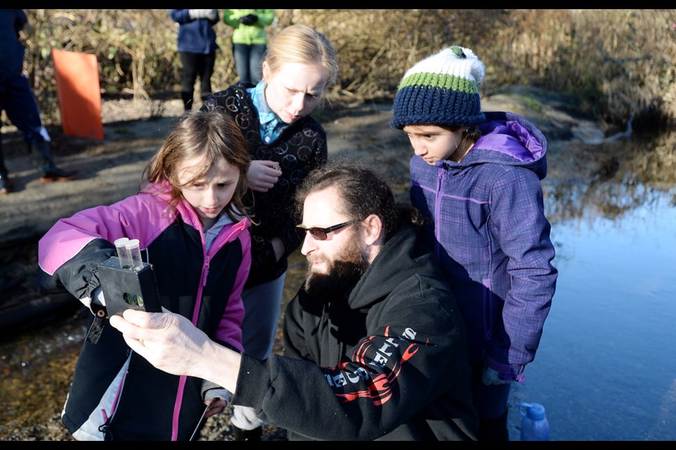 Andrew Kroll tests the PH levels in the Brunette River, watched by (from left) Hayley Kroll, Mackenna Henderson and Hannah Kroll.