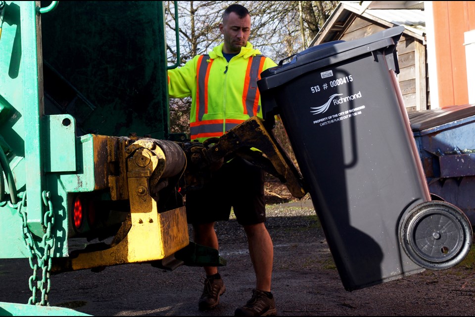 A Sierra Waste employee demonstrates the disposal of garbage using Richmond's new black trash cart system