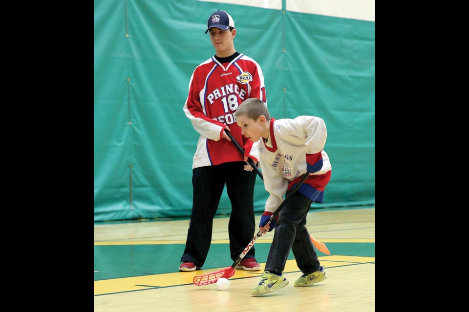 Robert Milford, 8, plays floorball with Cavin Tilsley of the Prince George Spruce Kings at Northern Sport Centre on Monday. Floorball was only one of the activities to take part in on Family Day, with wheelchair basketball, rugby, squash, and yoga as some of the other fun things that were available. Citizen Photo by James Doyle February 8, 2016