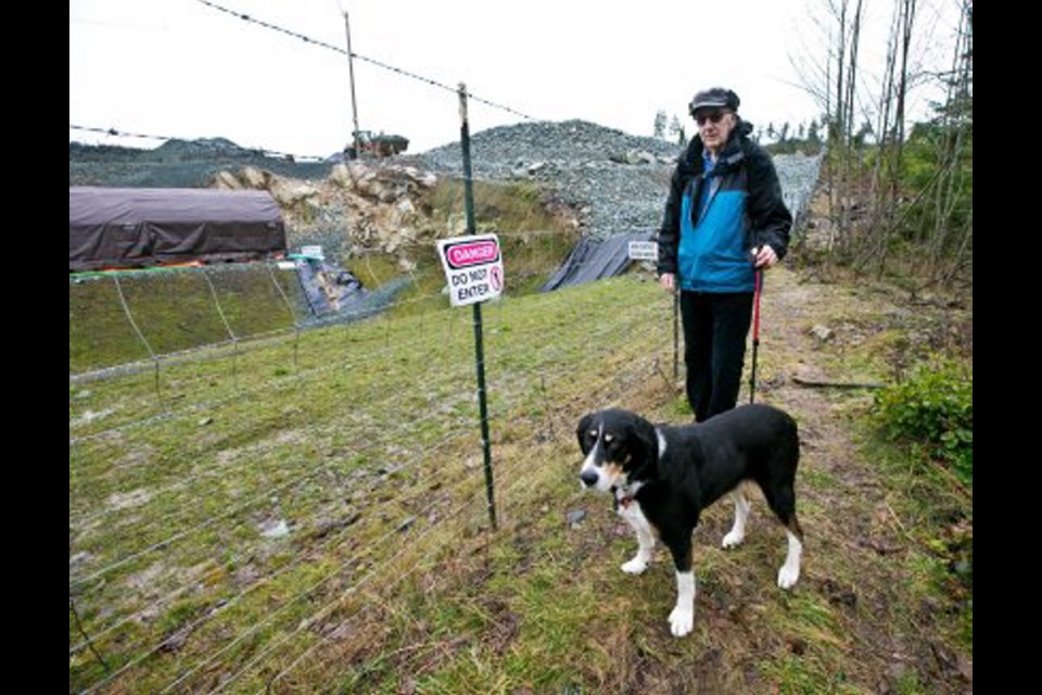 Ed Wiebe and his dog Xena patrol the fenceline of the Cobble Hill Holdings landfill site on Stebbings Road near Shawnigan Lake on Thursday.