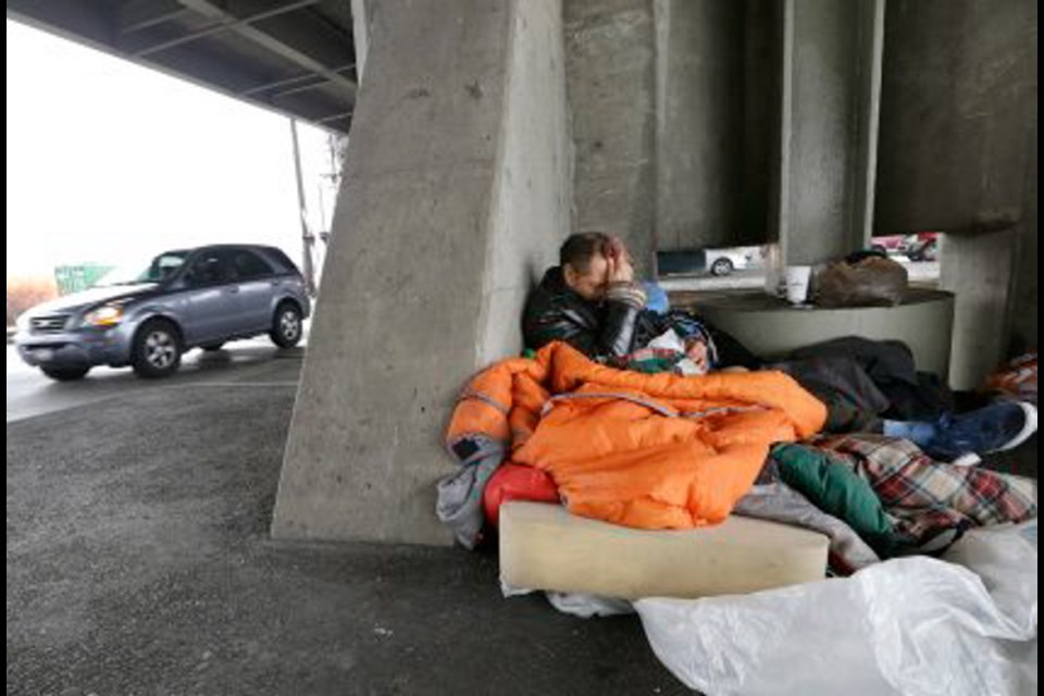 Aaron Benedict Morman wakes up beneath a viaduct as traffic passes him in Seattle. Morman said he's been homeless for more than 30 years.
