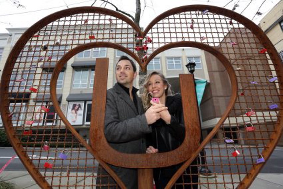 Karie Nix, 31, and Shane Snider, 40, try out the new love-locks sculpture at Uptown Shopping Centre.