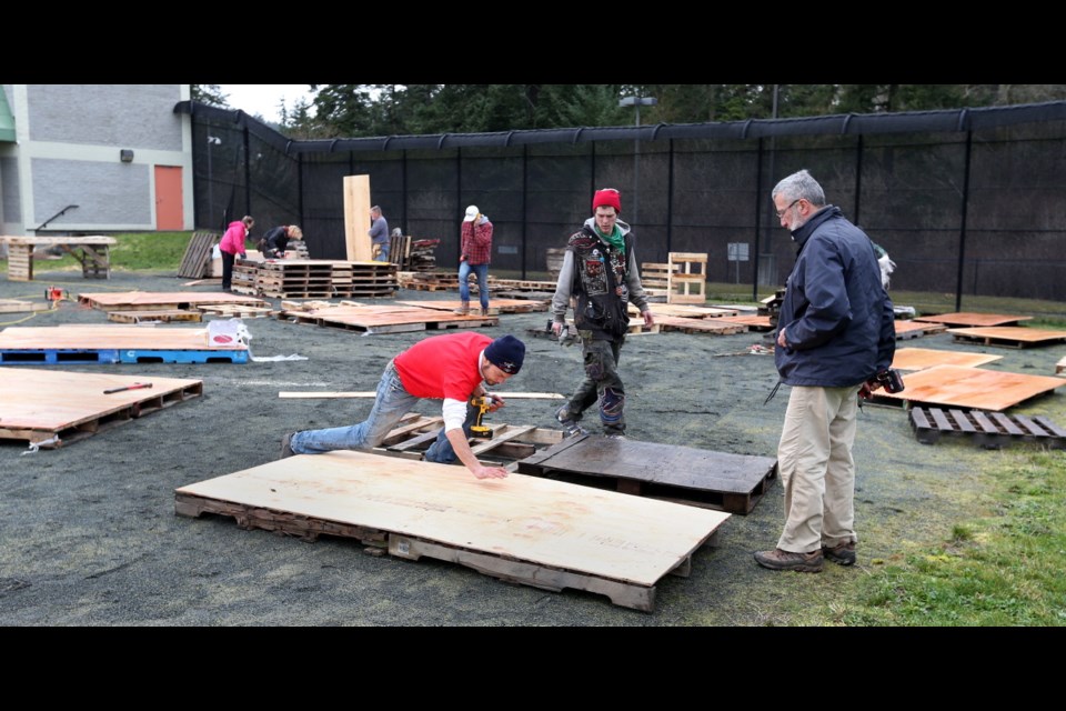 Our Place staff and volunteers build platforms for tents — as well as awnings and picnic tables — in preparation for the opening of Choices Transitional Home at the former youth custody centre in View Royal.