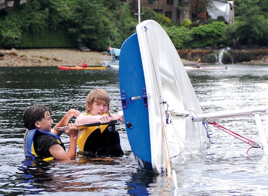 Liam Grehan and Sebastian Gitt put their boat's dagger board back in after a capsize.