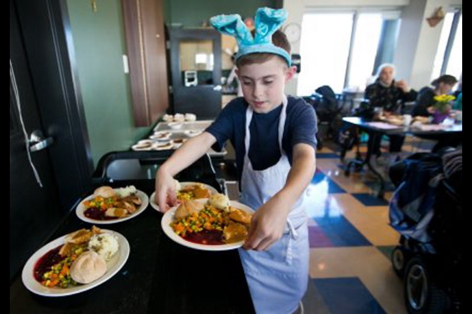Volunteer Anthony Schenk, 9, serves Easter dinners at Our Place on Tuesday. Almost 1,000 of Greater Victoria's less-fortunate people enjoyed a hot meal at the inner-city community centre.