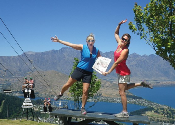 Glynis Webster and Theresa Clinton take the paper to a high point overlooking Lake Wakitipu in Queenstown, New Zealand.