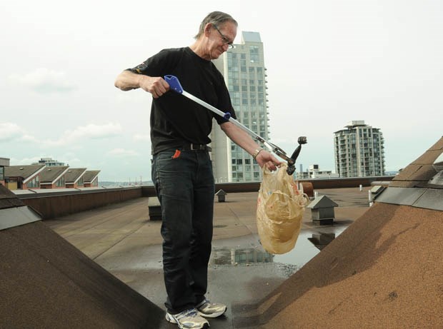 North Vancouver strata building manager Lloyd Martin cleans up bags of dog poop deliberately thrown on the roof of his building. photo Mike Wakefield, North Shore News