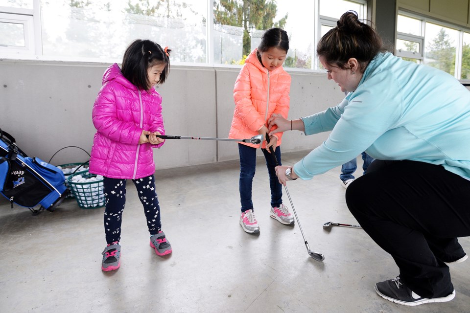 Assistant golf pro Kate Weir works with Little Linkers Elly and Ellen Hong.