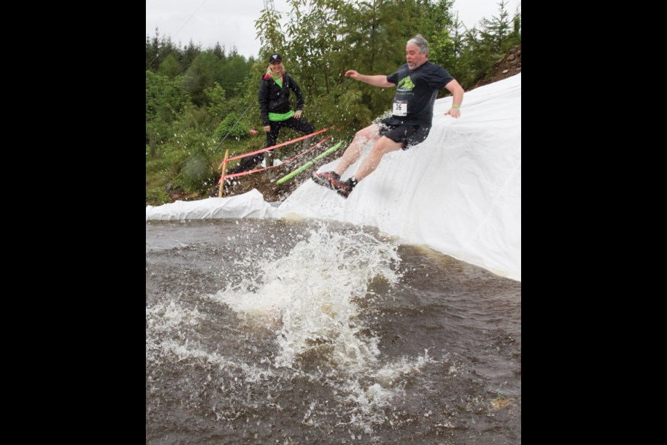 Chris Chalke is about to take an icy plunge in the waterslide obstacle in the second annual Mountain Grind race in Pender Harbour on April 23, which featured a longer track with new and improved obstacles. Volunteer Heather White watches from the safety of the sidelines.