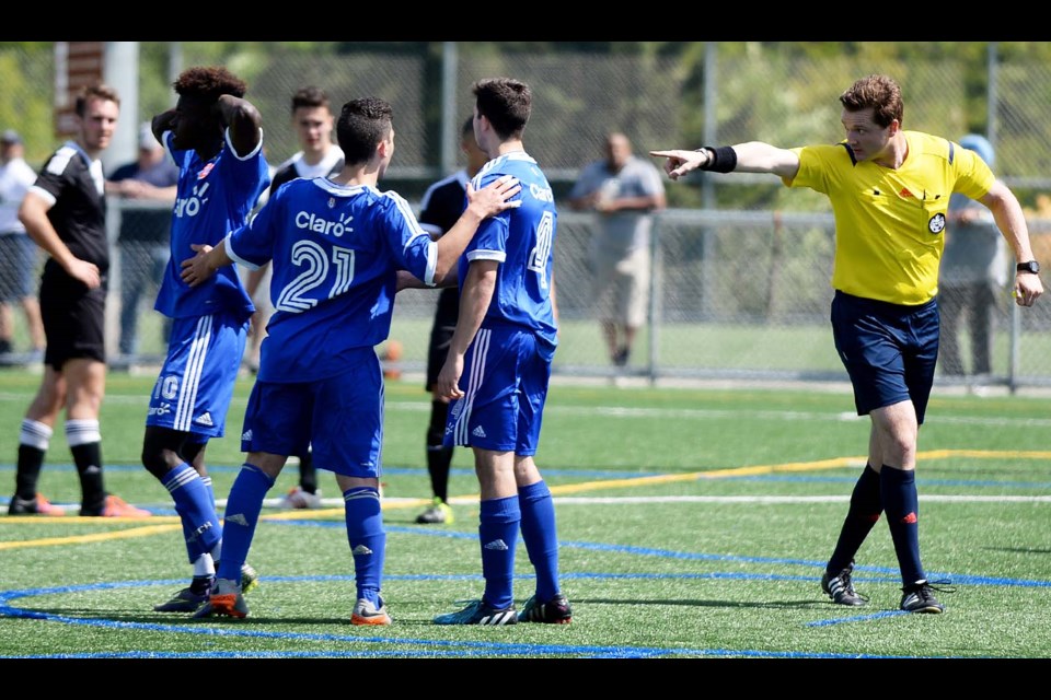 I see you: EDC Burnaby’s Joel Padmore (far left, in blue) and teammates Daniel Morello and Felipe Viera react after Padmore’s penalty kick was called back by referee Scott Milliquet due to a foot being inside the 18-yard box. Morello would retake the kick and score as they won their quarterfinal game at Burnaby Lake West.