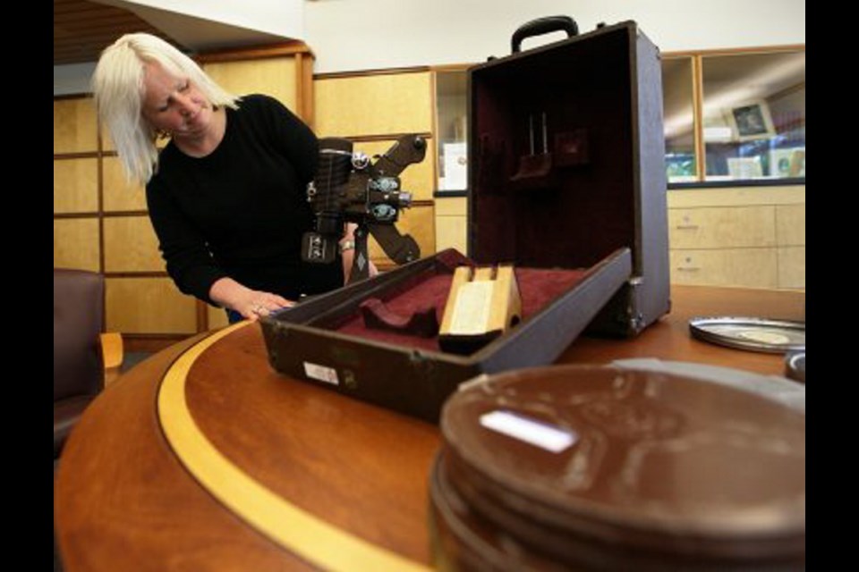 Archivist Lara Wilson with films of Chinatown and a projector used by Victoria businessman Mathew Ko in the University of Victoria's McPherson Library.