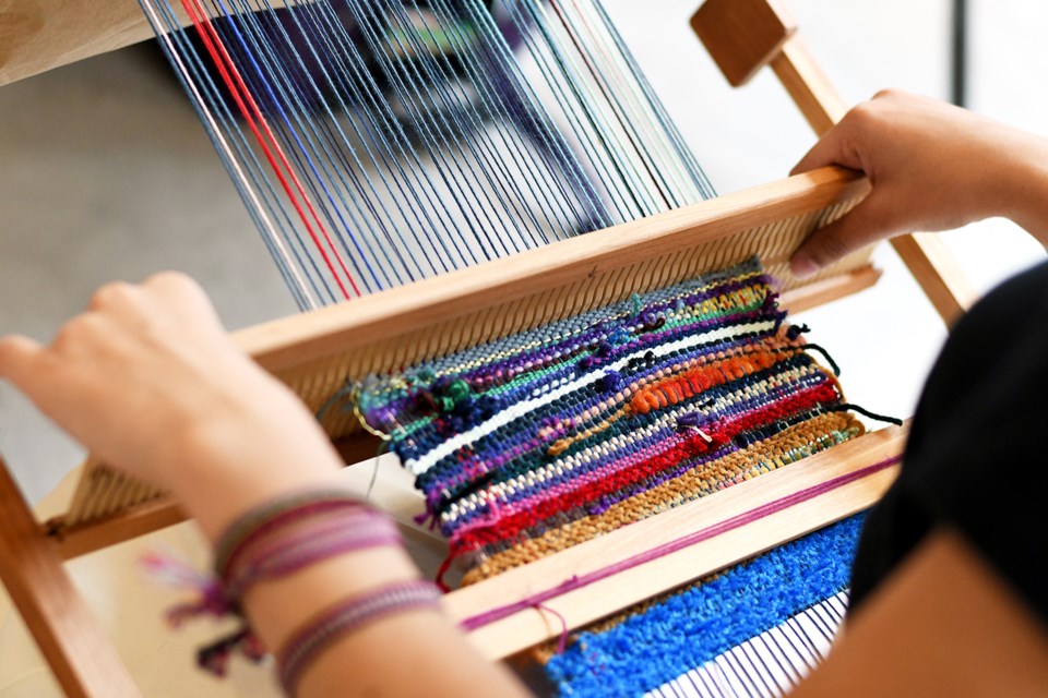Adrienne Neufeld works on a loom at the weaving workshop.