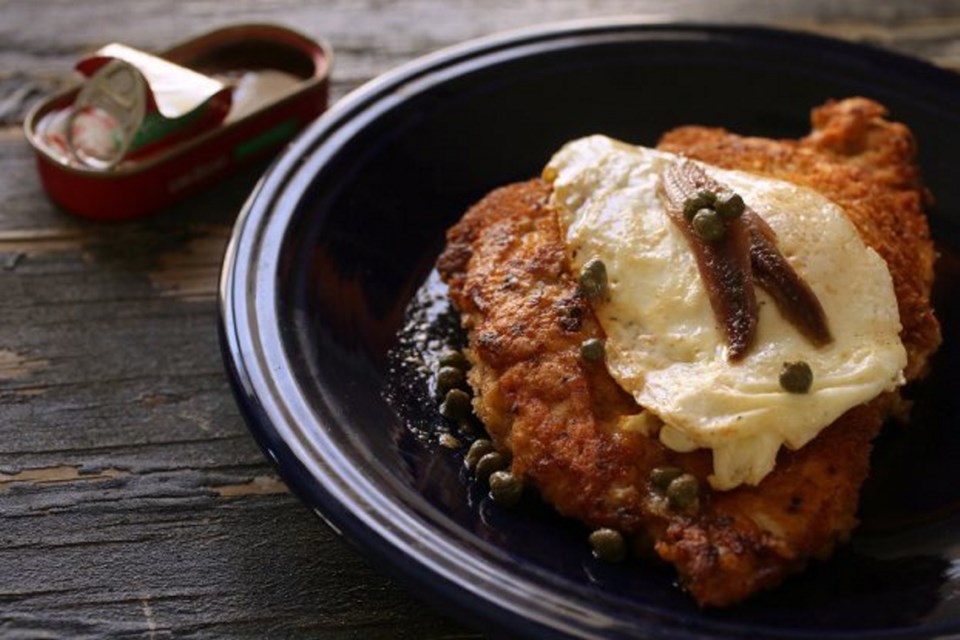 Chicken schnitzel is dressed with traditional Holstein toppings — a fried egg and anchovies.