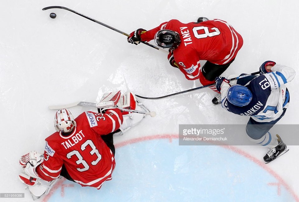 Chris Tanev clears a puck away from Cam Talbot