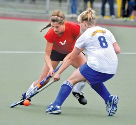 Handsworth's #8 Emily Booker (white) tries to check Carson Graham's Nicola Small in senior field hockey game at Rutledge Field at Ambleside.