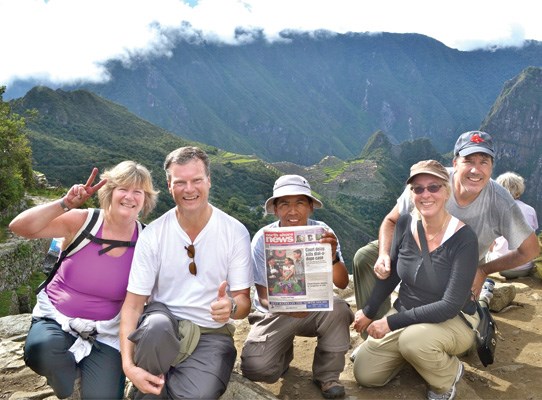 Susan and Peter Kvarnstrom, and Arlene and Dale Peniuk, take the North Shore News to the site of the Sun Gate, with help from their guide Edson (centre), while on a visit to Peru. Machu Picchu is in the background.